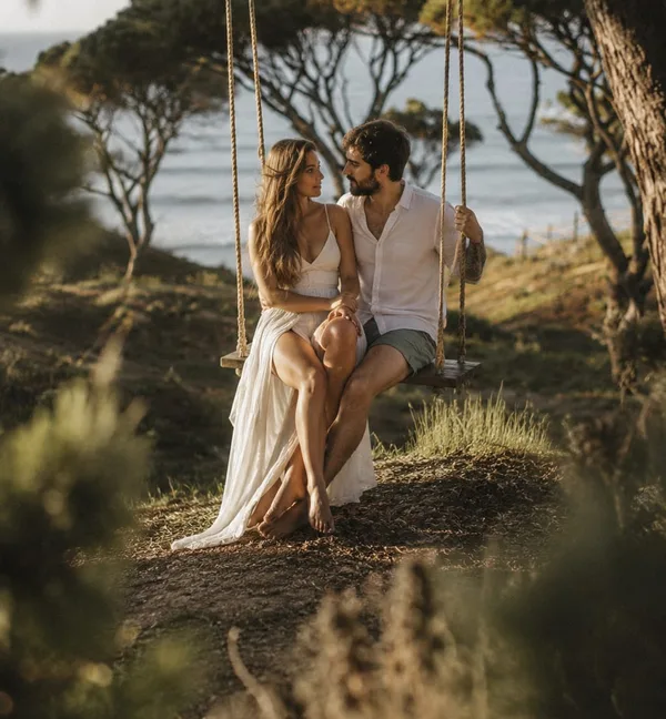 Um casal no baloiço entre os pinheiros, sobre o mar