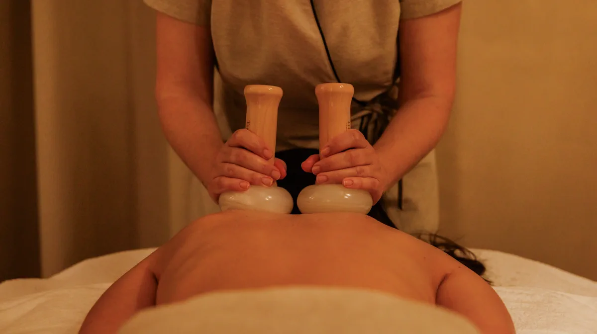 A therapist’s hands pressing two wooden massage tools during a treatment