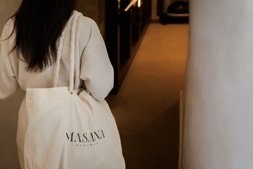 A white robe and a canvas bag in the softly lit corridor at NOOK