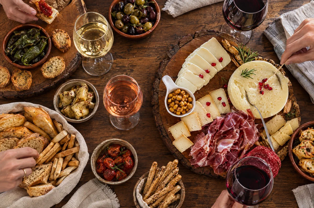 Boards of cheese, cured ham and roasted chickpeas with glasses of white, rosé and red wine